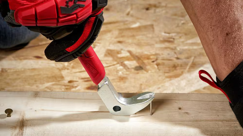 Closeup of a worker using a Milwaukee nail puller to remove a nail from a piece of lumber