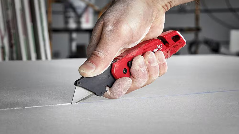 DIYer cutting drywall with a Milwaukee utility knife