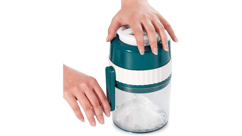 A person using a manual ice crusher on a white background.