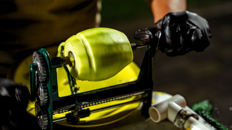 Black hand-cranked apple peeler loaded with a green apple.