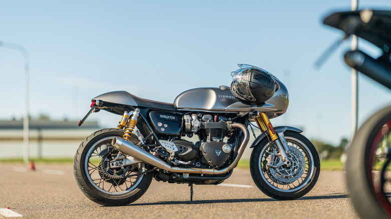 A gray classic Triumph Thruxton Cafe racer vintage bike parked on a road.