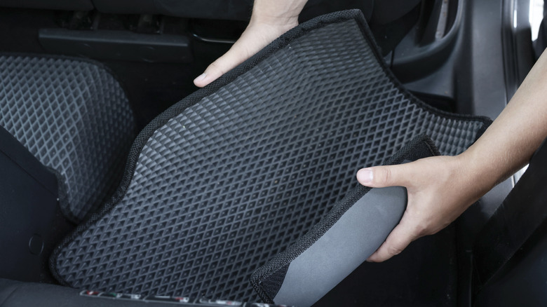 A car carpet being inserted onto the car floor