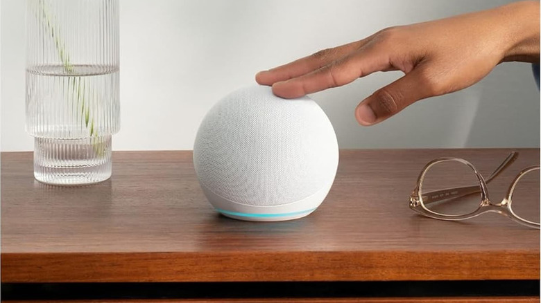 A hand taps a white Amazon Echo to pause music or snooze an alarm.