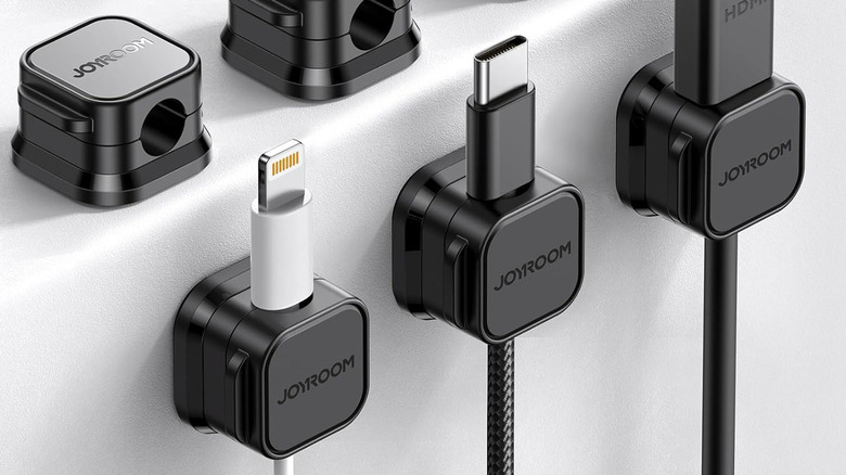 Several Joyroom cord holders attached to a white desk.