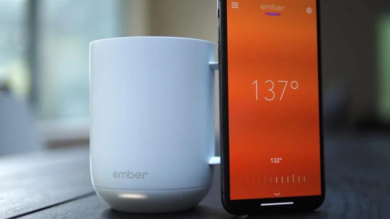 An Ember Mug next to a smartphone on a table.