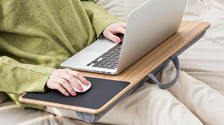 A woman sitting on a couch with a computer on a lapdesk.