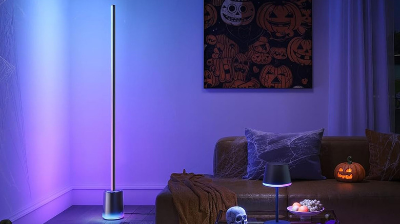 A Govee Floor Lamp 3 in a living room near a couch and shining pretty light.