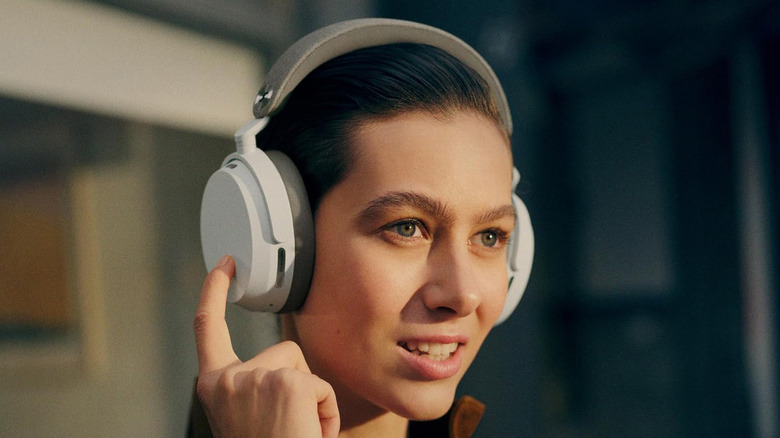 A woman using the touch controls on a pair of Sennheiser Momentum 5 Wireless headphones.