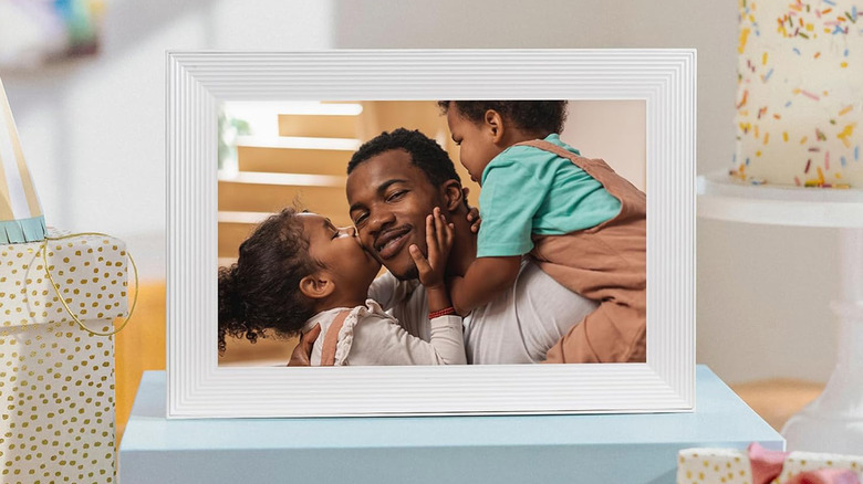 An Aura digital picture frame on a table in a brightly lit room.