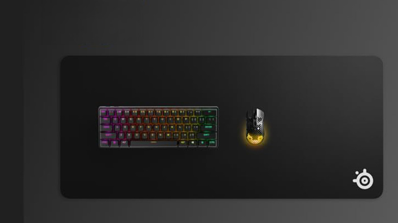 A SteelSeries large mouse pad with a mouse and keyboard on top of it.