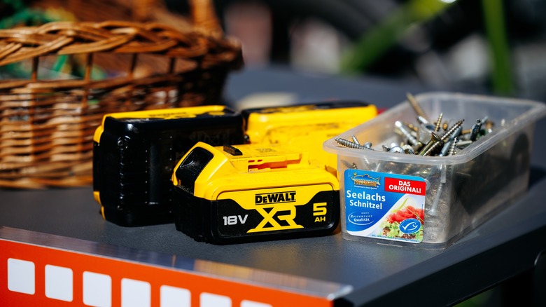 DeWalt batteries and a plastic box of screws on a work table