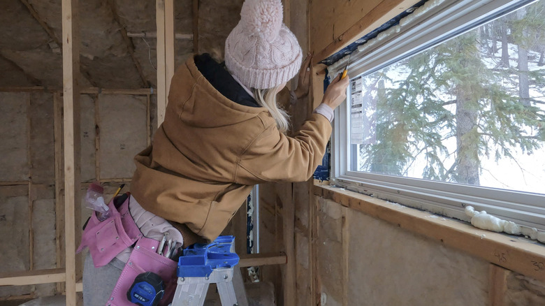 Woman in winter gear doing construction on a window
