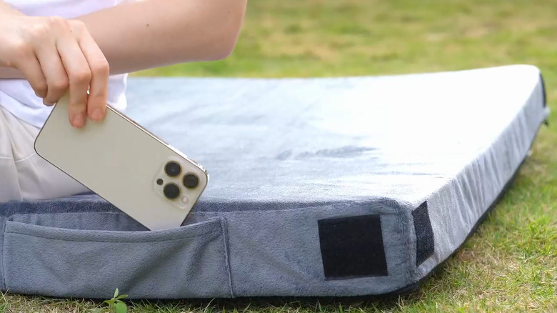 Side of the Cymula memory foam mattress on the ground, with a side sleeve for smartphones.