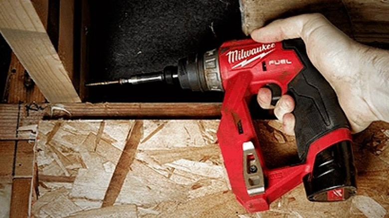 Using a drill driver to work on overhead wooden frames.