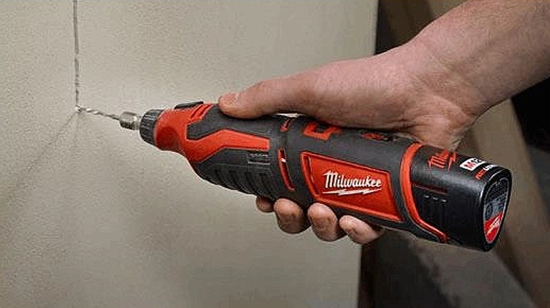 Using a rotary tool to cut through drywall.