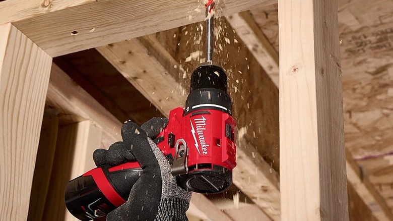 Drilling into an overhead wooden structure using a Milwaukee drill/driver.