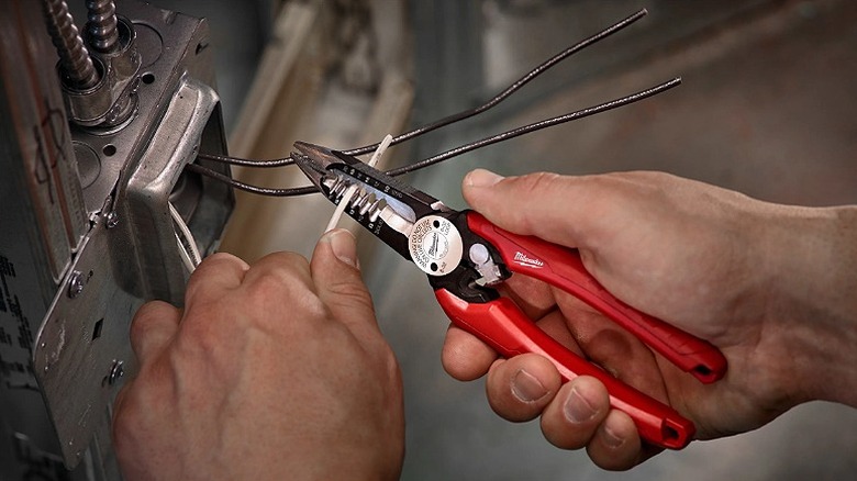 Cutting electrical wires with a plier.