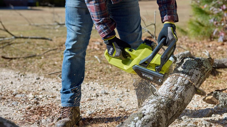 A person cutting a log with Ryobi 10-Inch Chainsaw.