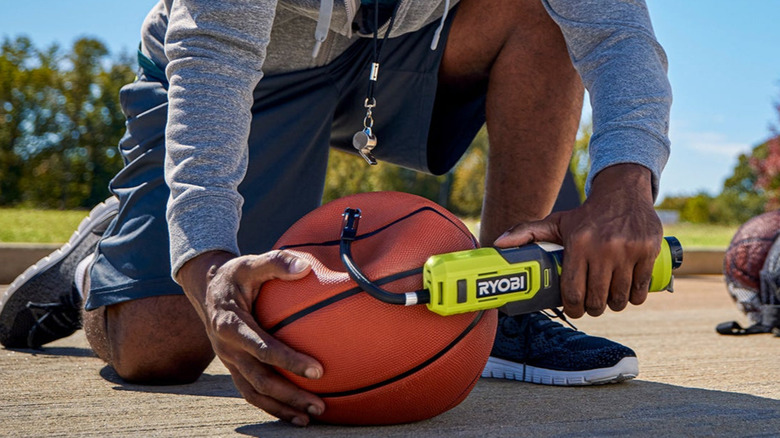 A person inflating a basketball with Ryobi Bike and Ball Pump.
