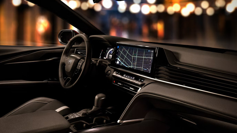 The infotainment display an steering wheel of the 2026 Toyota Camry Hybrid, photographed from the passenger seat at night.