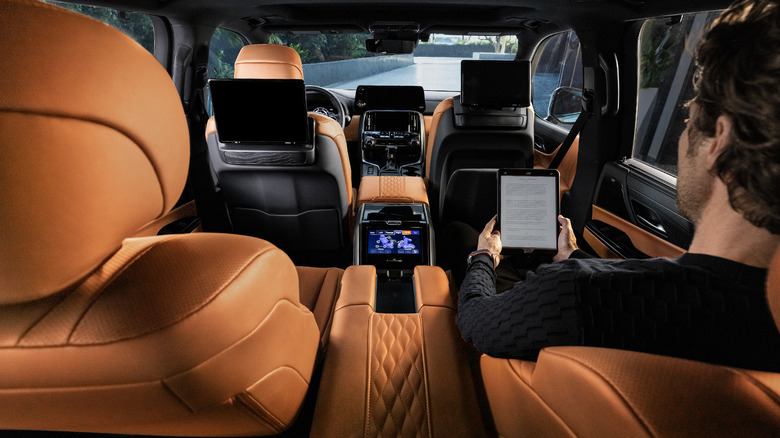 A person sitting in the rear passenger seat of the the 2026 Lexus LX, showcasing its rear-mounted screens
