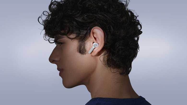 A boy wearing the Galaxy Buds4 Pro over a off-white background