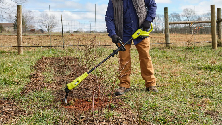 Man using a Ryobi battery hoe