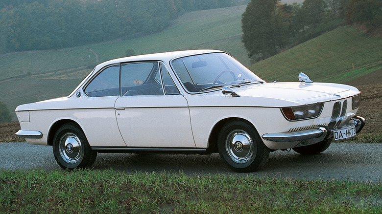 A white BMW 2000 CS parked on a tiny mountain road.