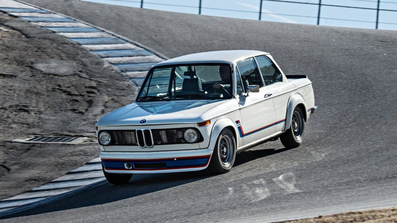A white BMW 2002 Turbo driving on track.