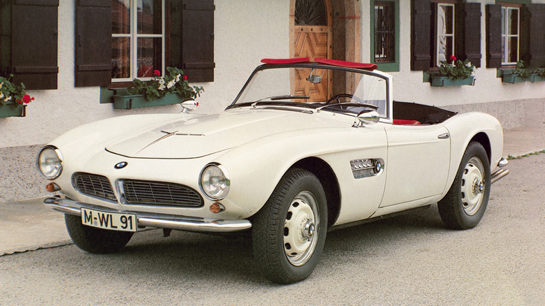 A white BMW 507 Roadster parked in front of a house.