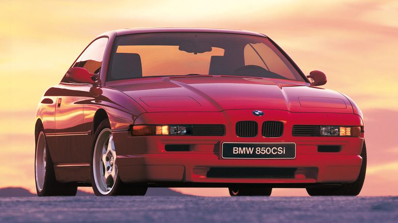 A red BMW E31 8 Series parked with sunset in the background.