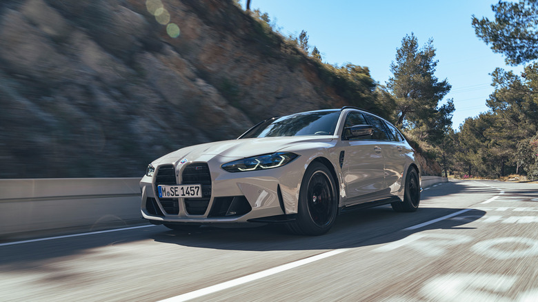 A gray BMW M3 Touring driving on mountain road.