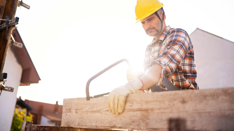 A person using a handsaw to cut a piece of wood