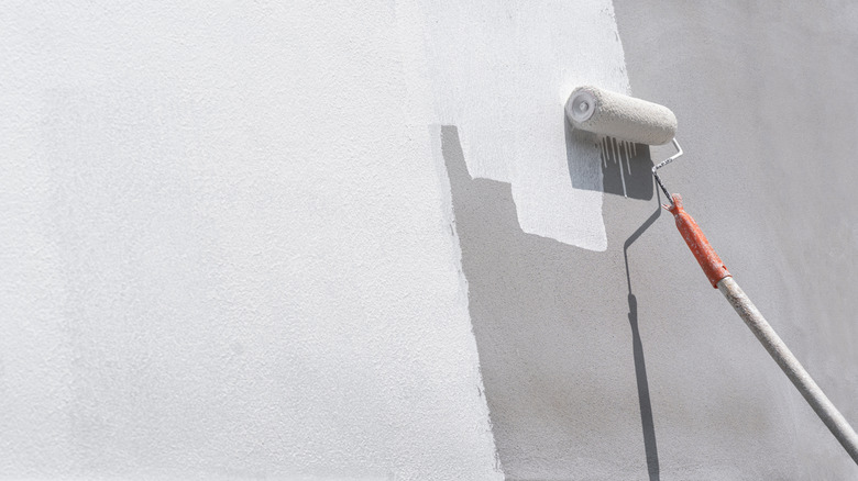 A roller applying paint to a wall
