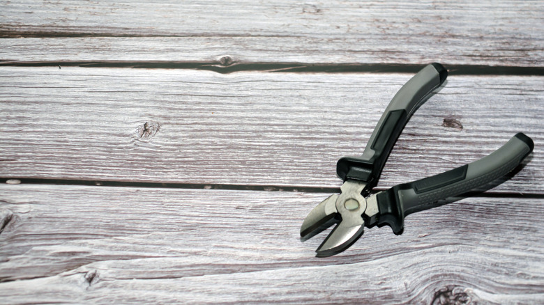 A pair of silver pliers on a wooden table