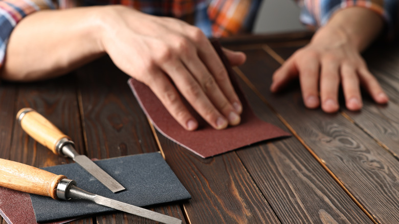 A person using sandpaper on a table