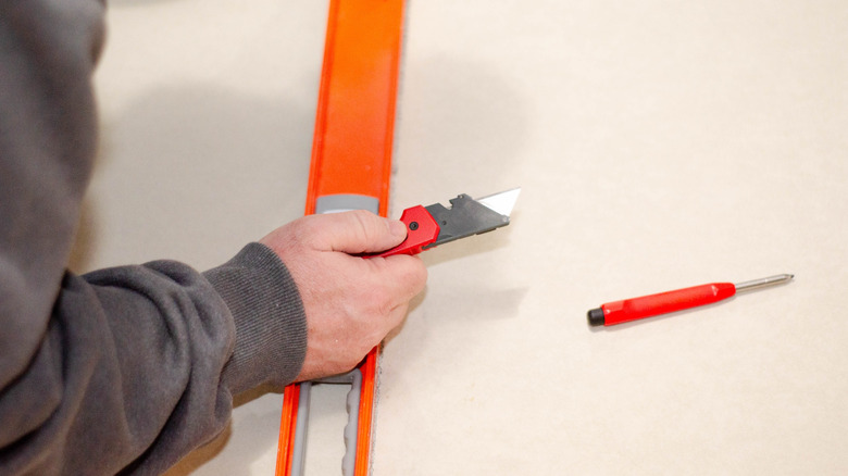 A person holding a red and black utility knife