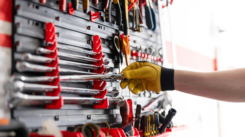 A person picking a wrench from a selection in a toolbox