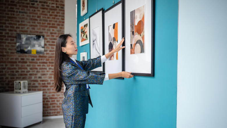 Woman adjusting photo on a gallery wall