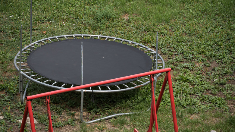 Trampoline behind a red-framed swing set