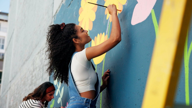 Two women painting an outdoor mural