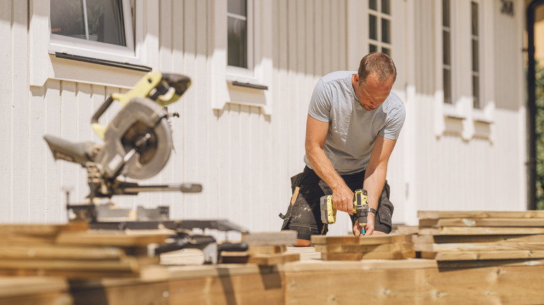 Man using tools to build a deck on a house