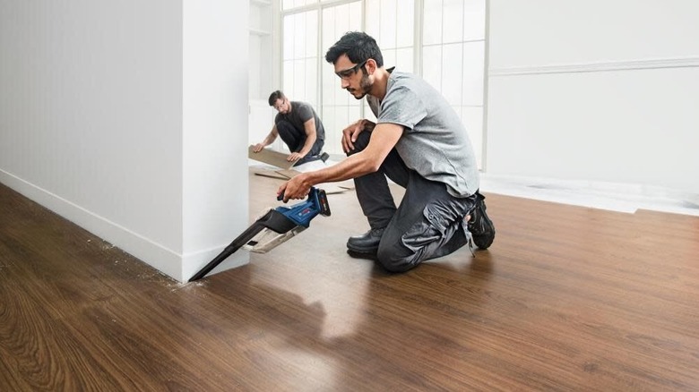 Handheld vacuum being used to clear up dust on the side of wall corner