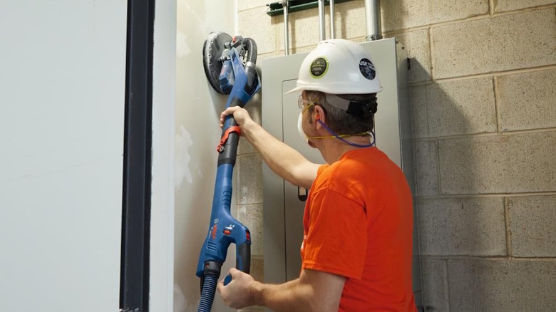 Construction worker using the Bosch sander on a drywall
