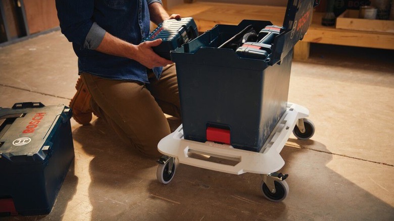 A person putting a toolbox on top of the transport dolly