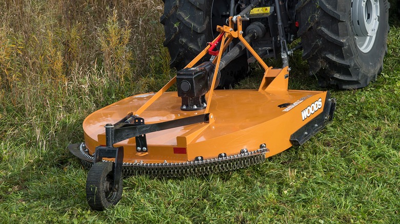 Rotary brush cutter by Woods being pulled by a tractor.