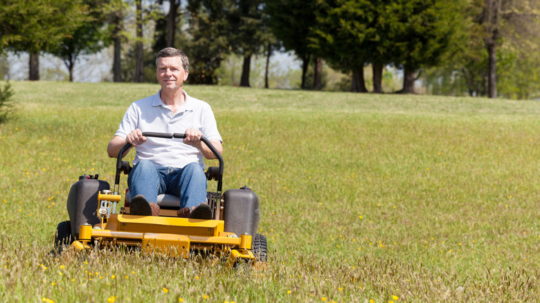 Man cutting lawn on a zero turn riding mower.