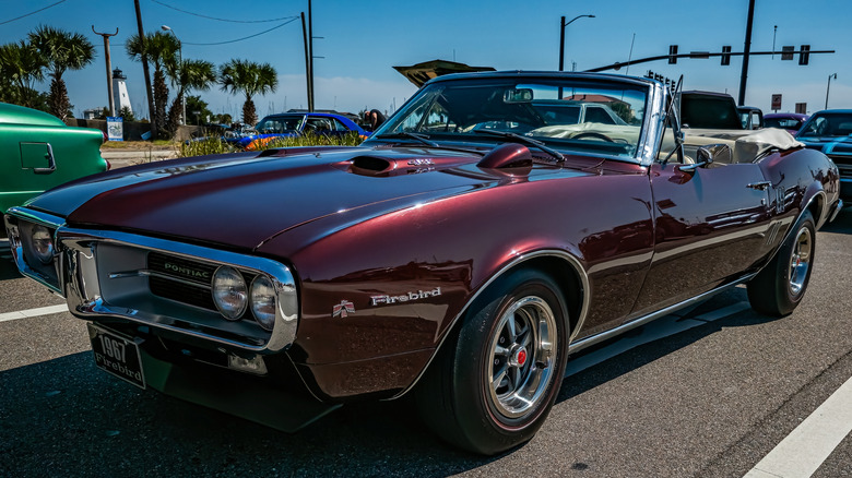 1967 Pontiac Firebird convertible at classic car show, front 3/4 view, burgundy exterior