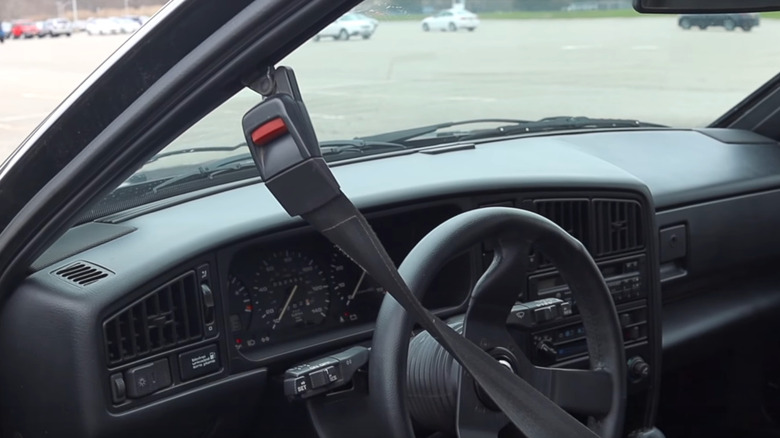 Interior of a 1988 Volkswagen Corrado showing the driver's side with a motorized automatic shoulder seatbelt on the door frame.