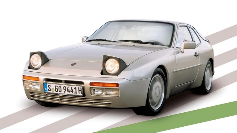 A silver Porsche 944 sports coupe with its pop-up headlights raised.